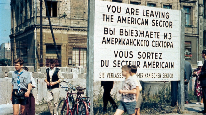 West Berliners walk in front of the Berlin Wall at the Allied Checkpoint Charlie in July 1963.