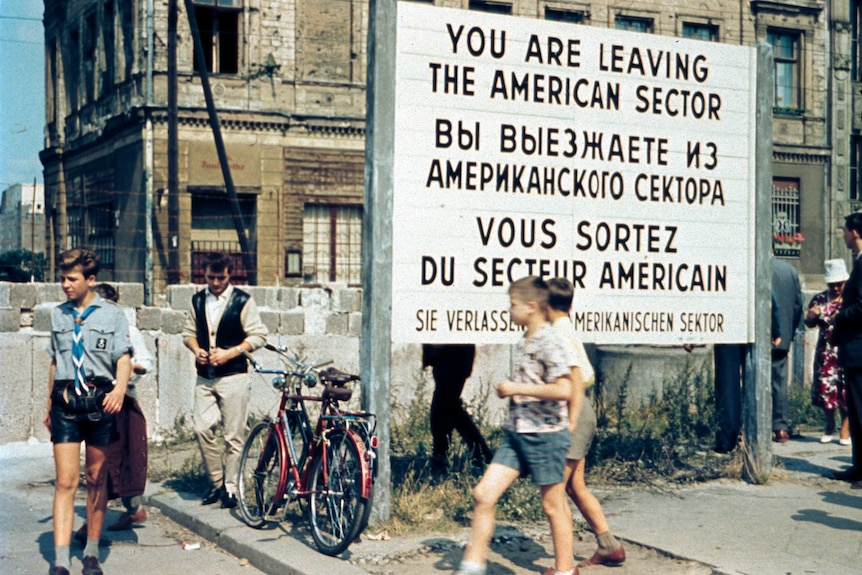 West Berliners walk in front of the Berlin Wall at the Allied Checkpoint Charlie in July 1963.