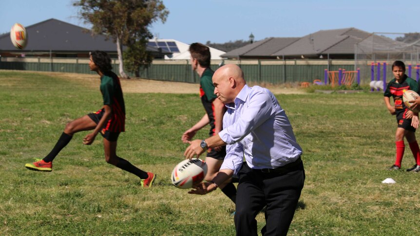 NSW Education Minister Adrian Piccoli playing football with high school students.