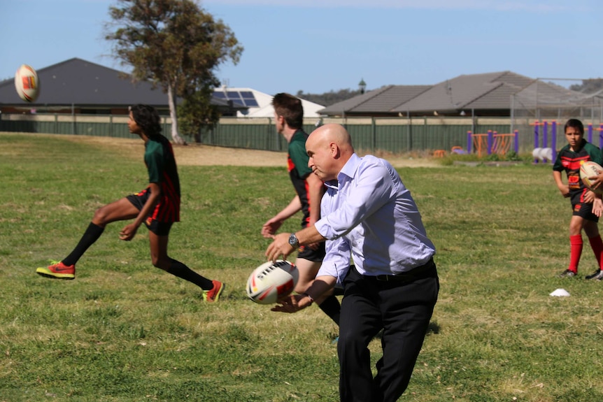NSW Education Minister Adrian Piccoli playing football with high school students.