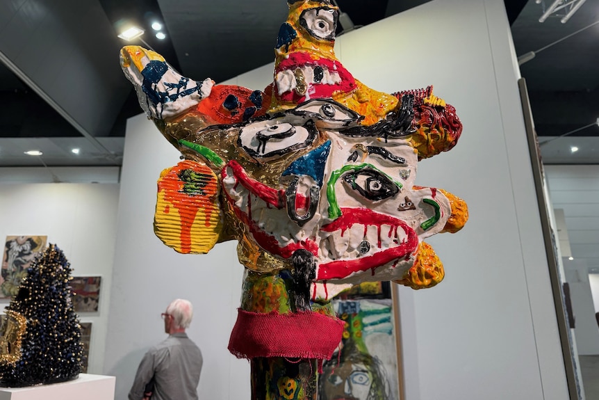 A large, colourful sculpture with distorted facial elements in an art gallery.