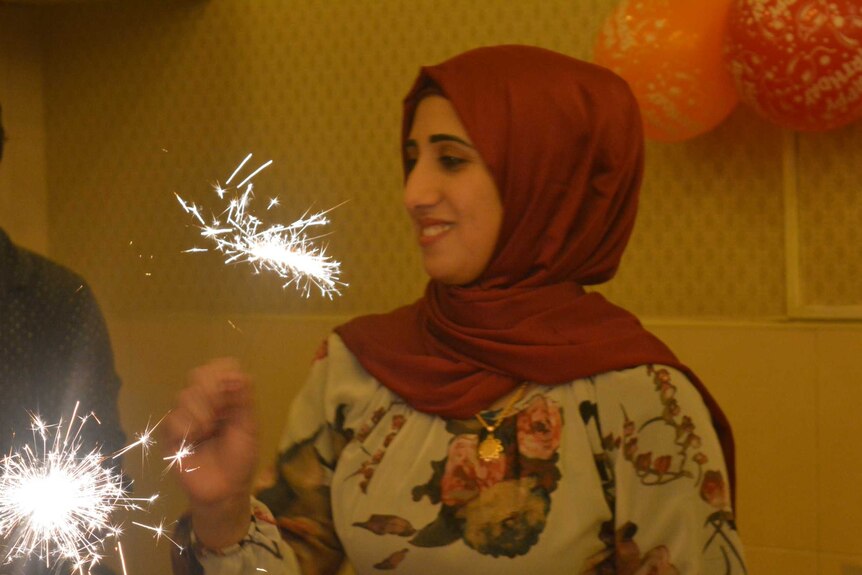 Yasmin Zalghanah smiles while holding a sparkle, with balloons in the background.