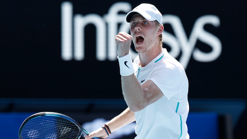 A Canadian male tennis player pumps his left fist as he celebrates winning a point.