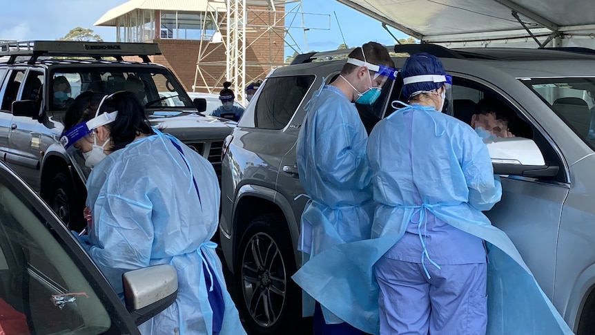 Covid testers in full ppe at cars