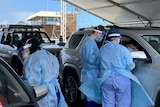 Covid testers in full ppe at cars