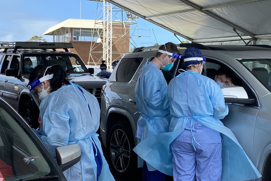 People in PPE attend drivers at a COVID testing clinic.