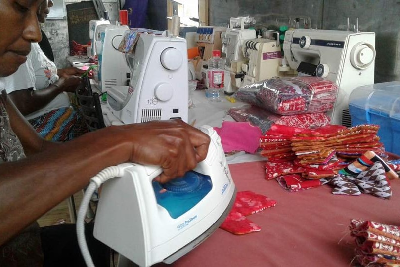 Volunteer using an iron whil making a sanitary pad