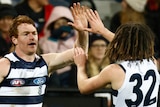 Two Geelong AFL players congratulate each other after a goal was kicked.
