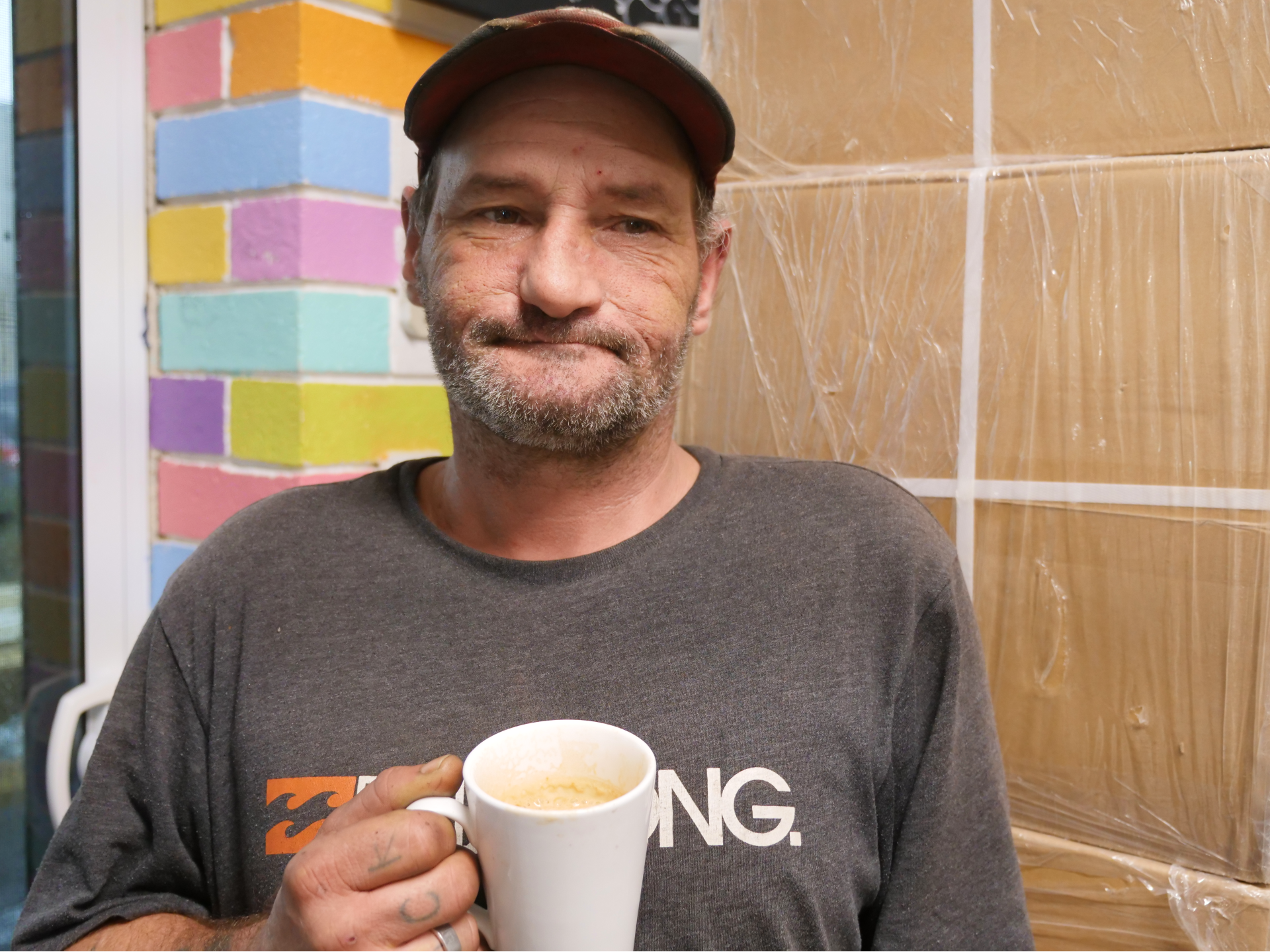 A man stands in front of a wall with a coffee