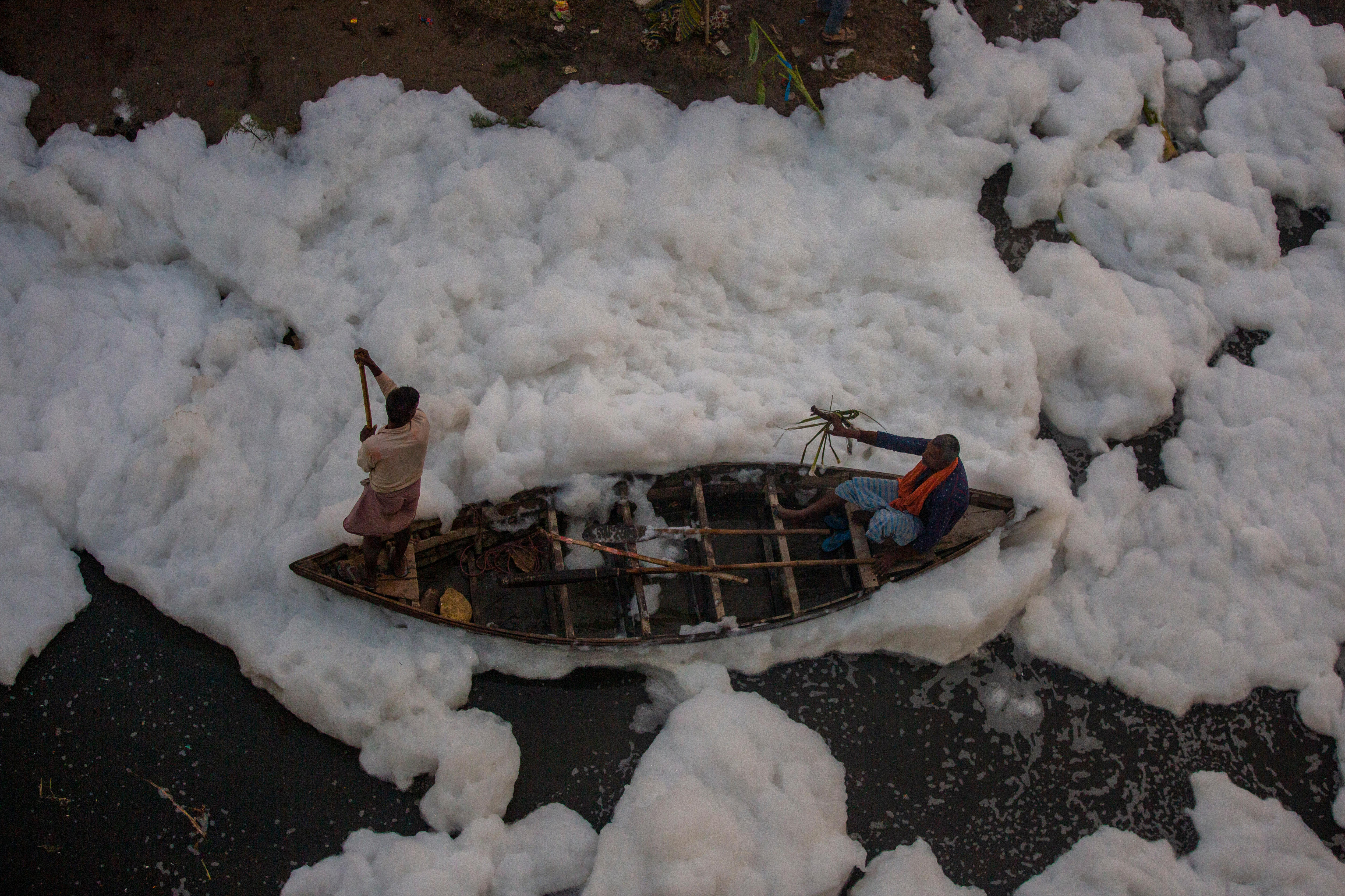 A man rows a boat in a polluted river