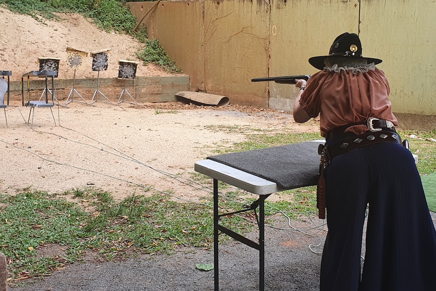 Lady dressed as a cowgirl and shooting at the gun range