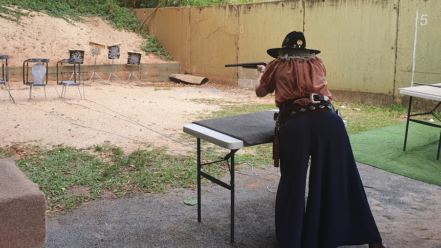 Lady dressed as a cowgirl and shooting at the gun range