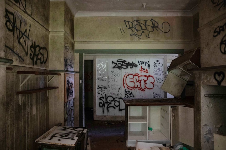 graffiti and abandoned furniture inside a dark house