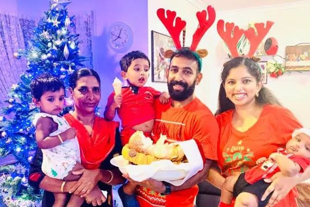 The six family members stand wearing Christmas themed clothing