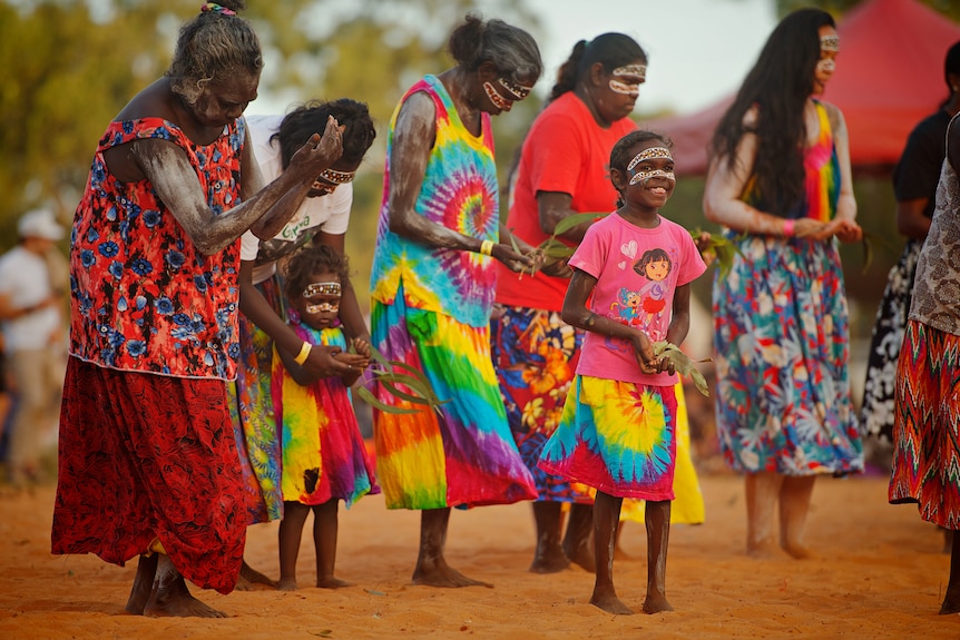 A group of people dressed in rainbow tie dye dancing