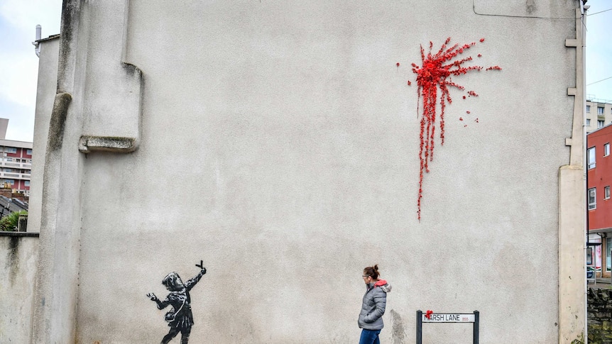 A woman walks past a new artwork on the side of a house in Bristol.