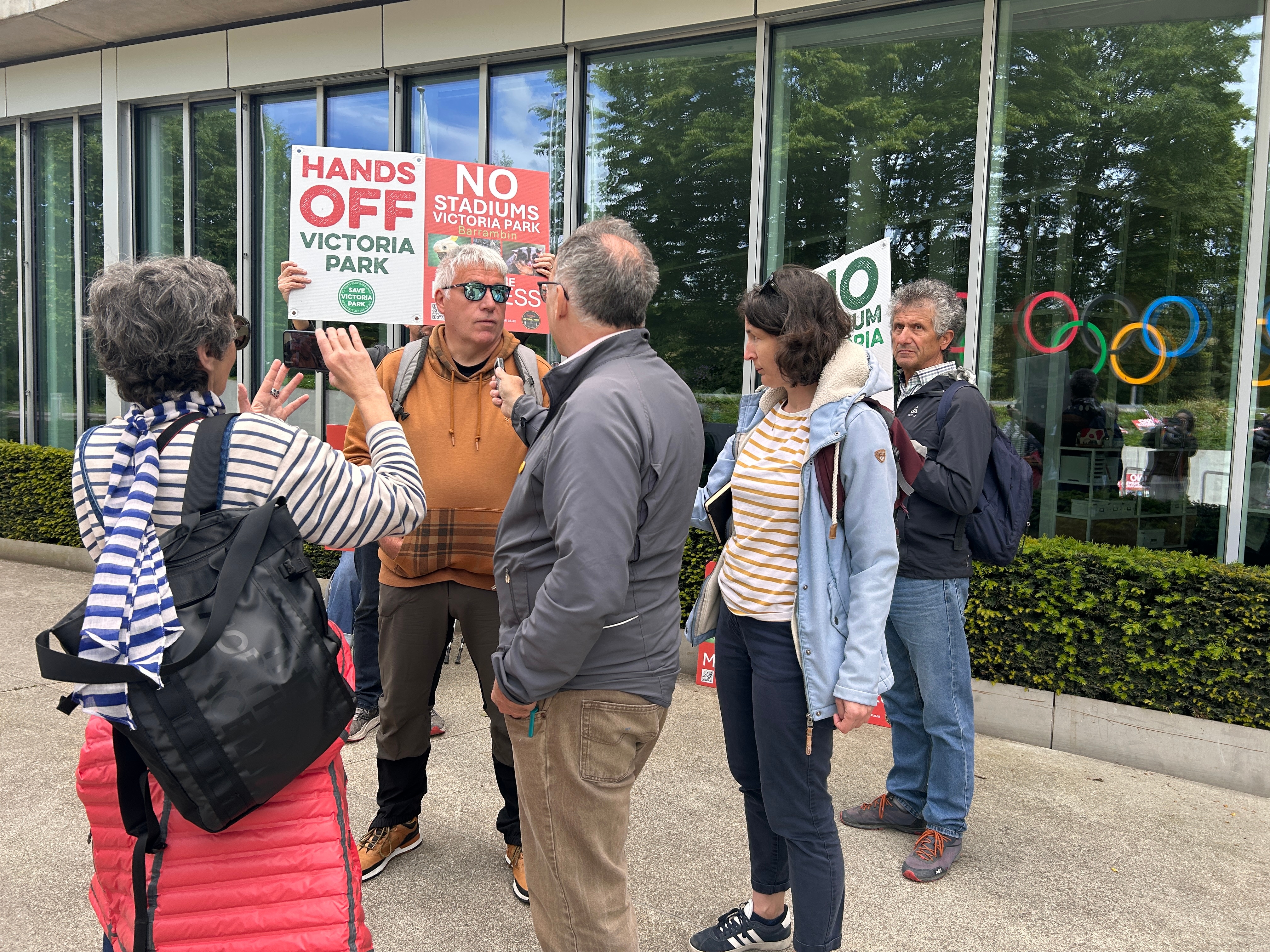 A group of protesters outside the IOC headquarters in Switzerland holding up signs.