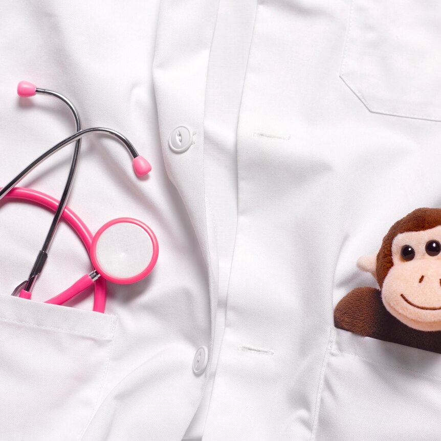  In the pockets of a white coat, there's a little stuffed monkey and a pink stethoscope nestled inside.