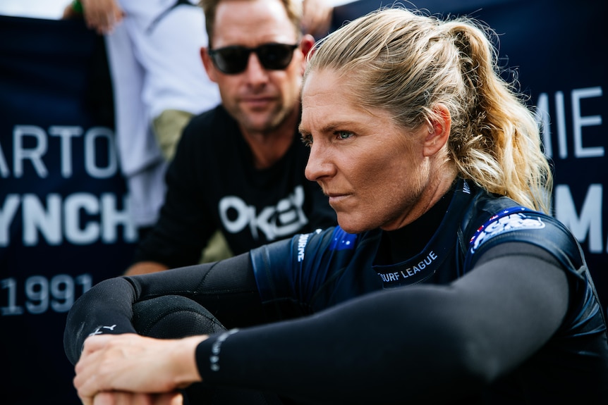 La surfista australiana Steph Gilmore se sienta con los brazos alrededor de las rodillas mirando a lo lejos mientras espera para competir.