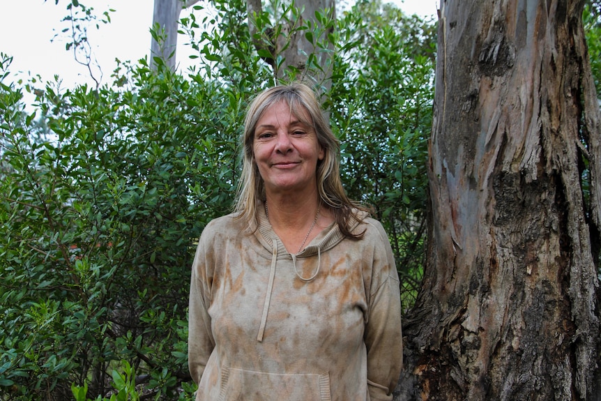 A woman up against a backdrop of green and gum trees