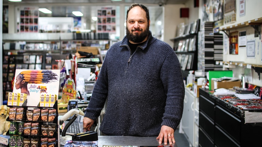 Castlemaine video shop owner Scott Dew standing behind the counter of his shop.