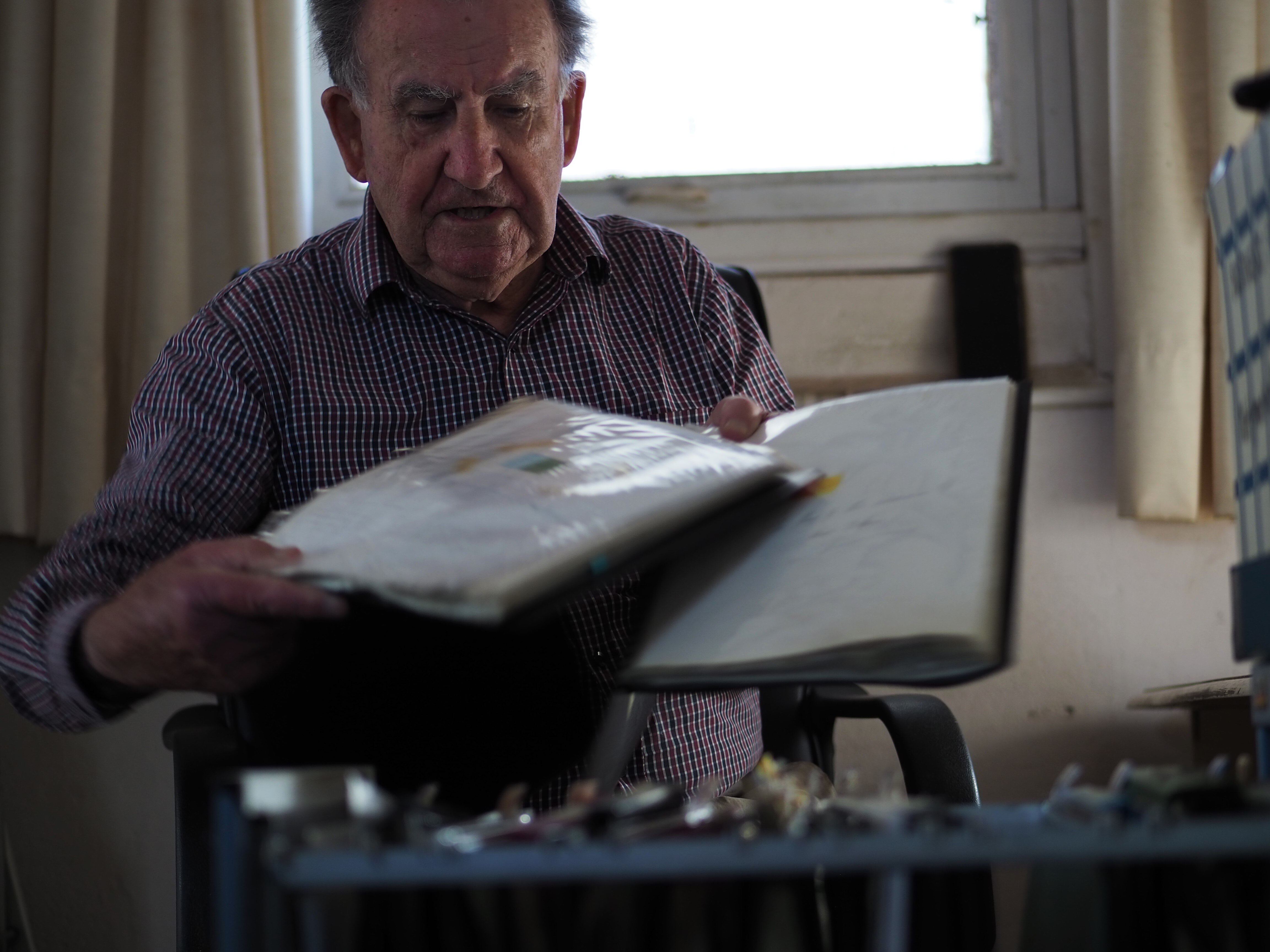 Un hombre mayor mira dos carpetas que contienen hojas sueltas.