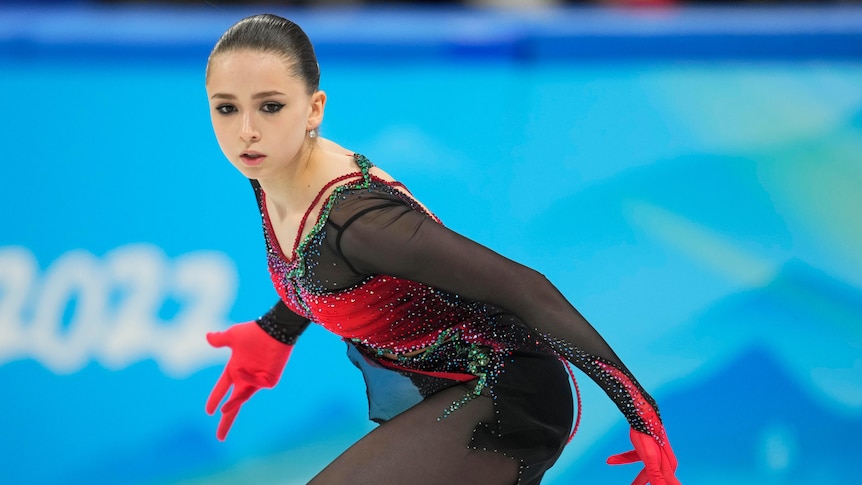 A Russian figure skater looks down the ice, holding her hands out from her sides in the middle of a Winter Olympics routine.