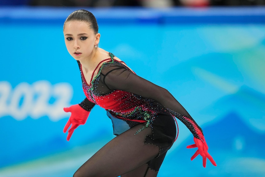 A Russian figure skater looks down the ice, holding her hands out from her sides in the middle of a Winter Olympics routine.