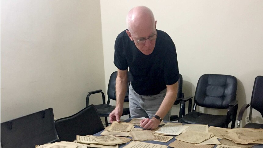 Columba Stewart examines ancient documents spread on a table