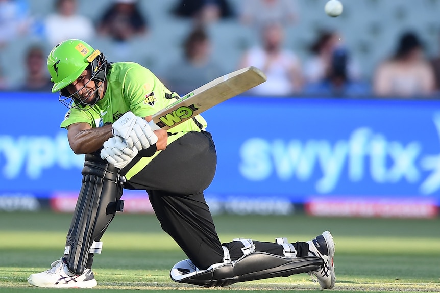 Jason Sangha plays a sweep shot, grimacing