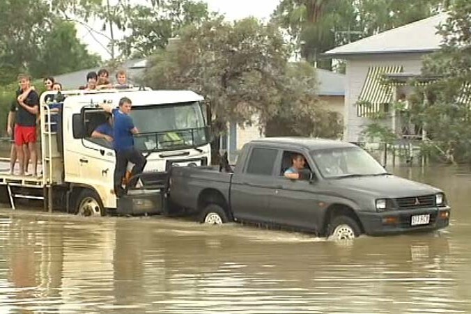 A truck and a car drive through floodwaters in Roma