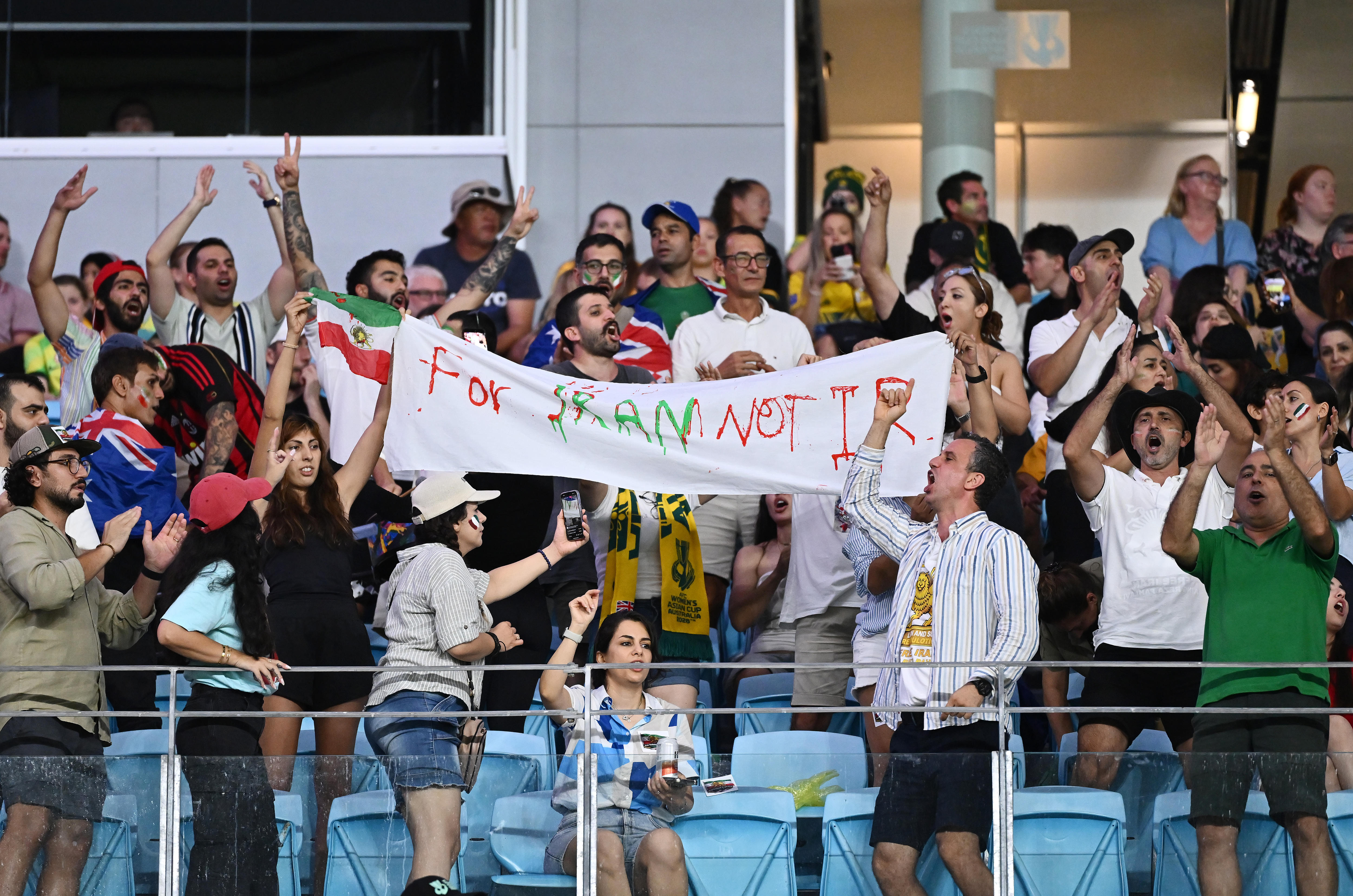 Fãs na multidão seguram uma placa que diz 'Para o Irã, não para IR'