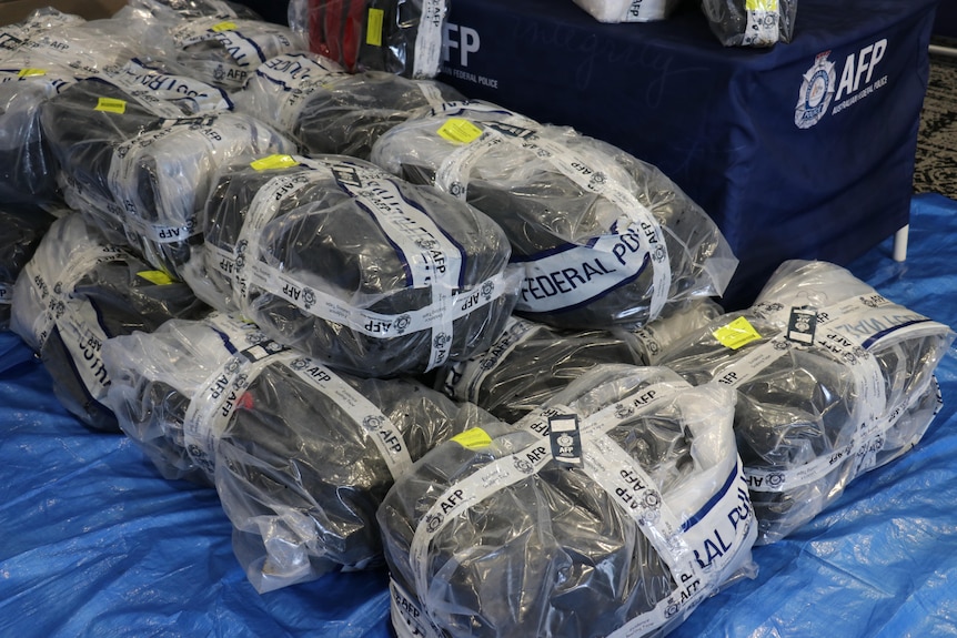 A close-up shot of large plastic-wrapped packages containing cocaine and taped up with Australian Federal Police tape.