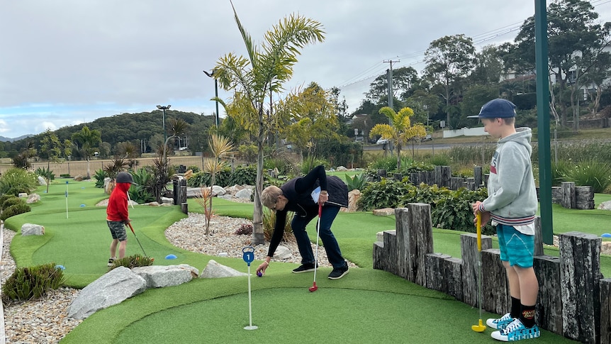 Two grandsons under five playing mini golf with their Grandma. 