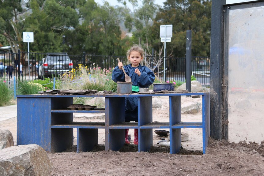 Waimea Heights Primary School Kindergarten student 'cooking' in the outdoor kitchen with mud June 2016