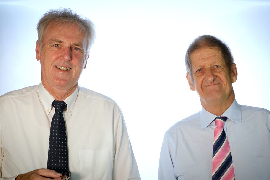 Roy Slaven and HG Nelson, wearing shirts and ties, stand in front of a white background.