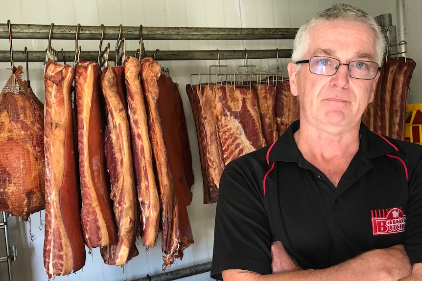 Des Barritt standing, arms folded in his cool room, in front of bacon that he will have to destroy.