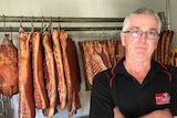 Des Barritt standing, arms folded in his cool room, in front of bacon that he will have to destroy.