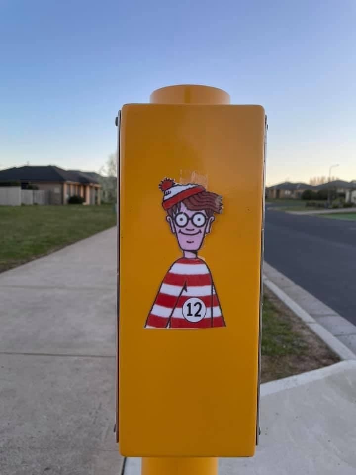 A cartoon character with glasses and a beanie stuck to a pole.