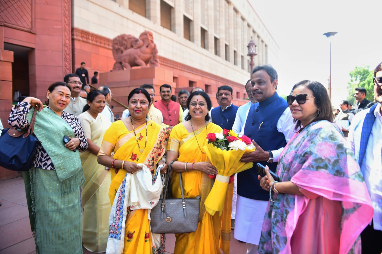Indian females dressed in colourful sarees stand together smiling