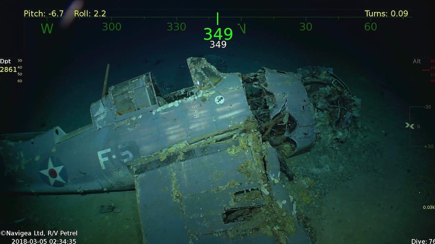 A decaying aircraft lies at the bottom of the ocean. It is covered in barnacles.