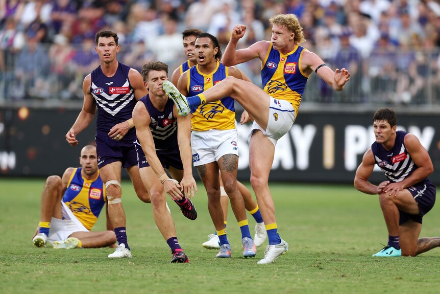 Reuben Ginbey kicks the ball as a crowd of Dockers and Eagles players contest nearby