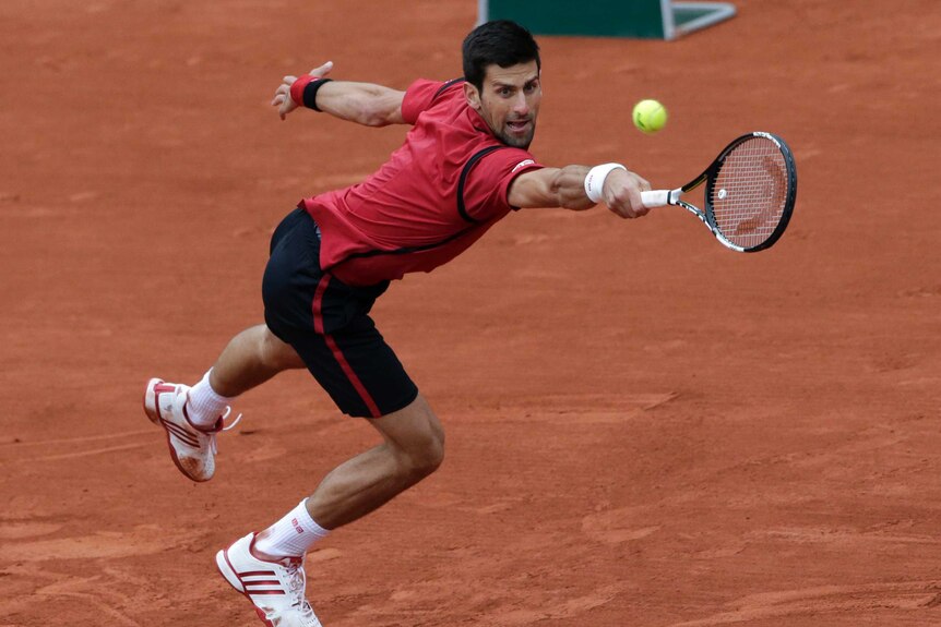 Novak Djokovic reaches out with his tennis racquet.