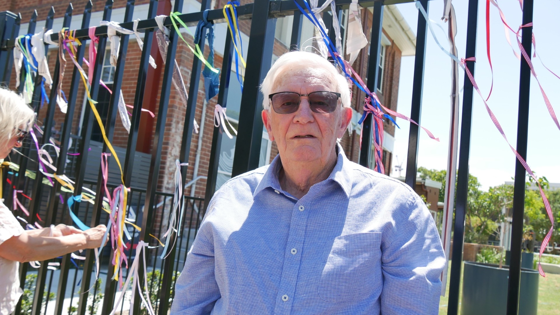 Hombre frente a la valla con cintas.