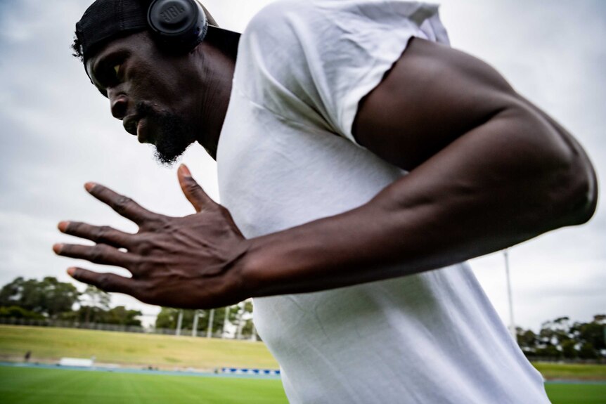 Abdoulie Asim wears headphones, a backwards cap and a white t-shirt as he runs.