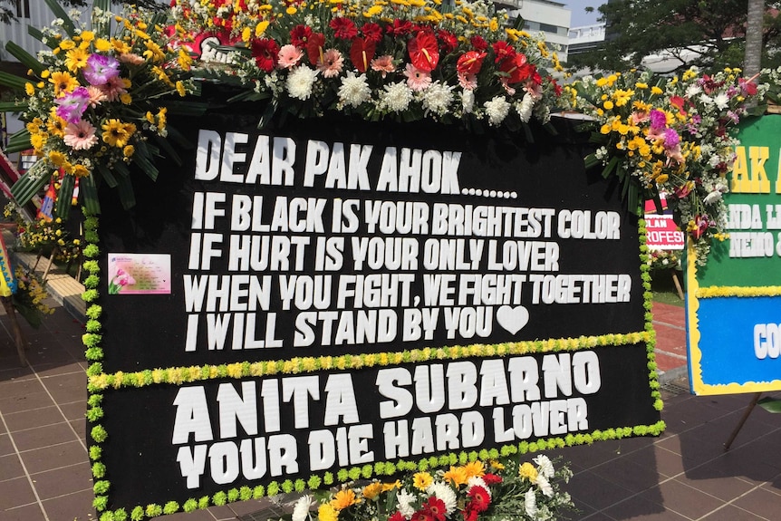 A black and white sign reads: "Dear pak ahok if black is your brightest colour, if hurt is your only lover...i will stand by you