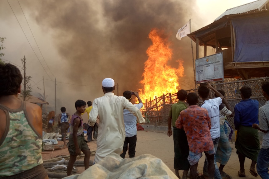 Les villageois s'affolent alors qu'une grande flamme engloutit le village devant eux.