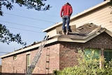A man inspecting roofing works on top of a house
