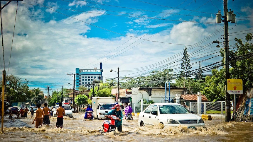 People trying to make their way down a flooded street.