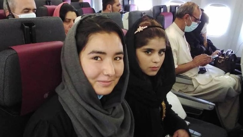 Two young women seated on a plane.